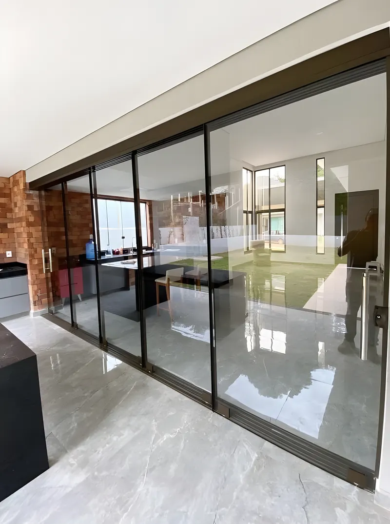 Porta de correr de quatro folhas de vidro fechando uma sala ampla