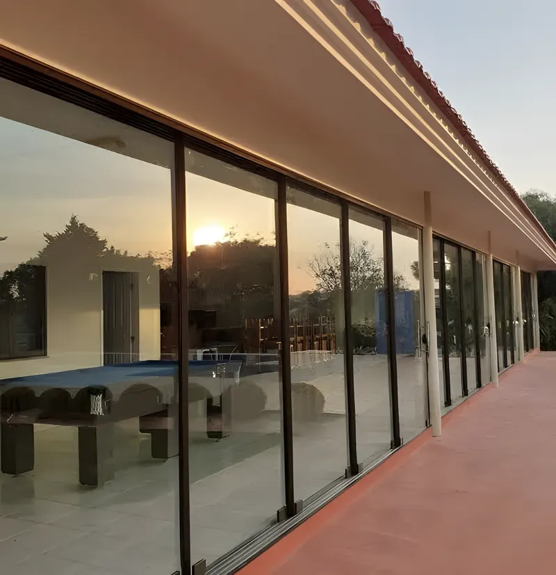 Sequência de portas de vidro em uma varanda refletindo o pôr do sol